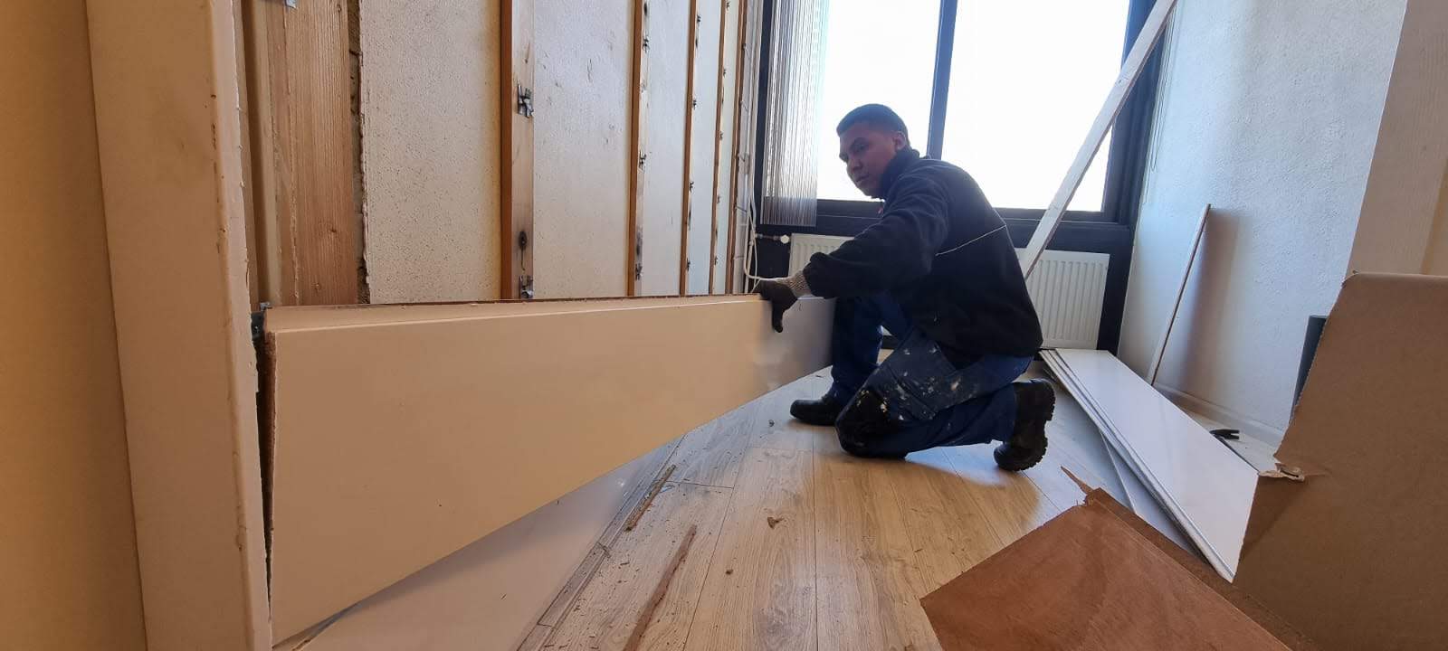 Team member aligning a long wall panel in a room under renovation
